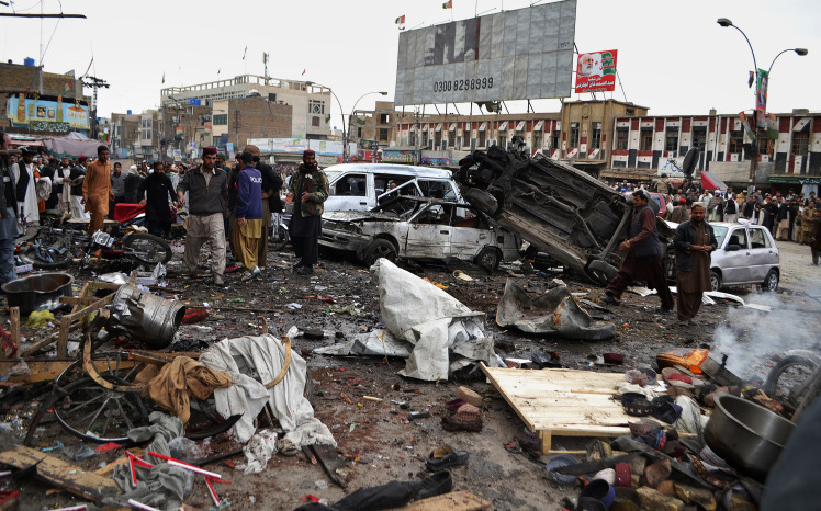 Pakistani police officers and local residents gather at the site of bomb blast in Quetta, Pakistan, Thursday, Jan. 10, 2013. A bomb targeting paramilitary soldiers killed scores of people in southwest Pakistan, officials said. (AP Photo/Arshad Butt)