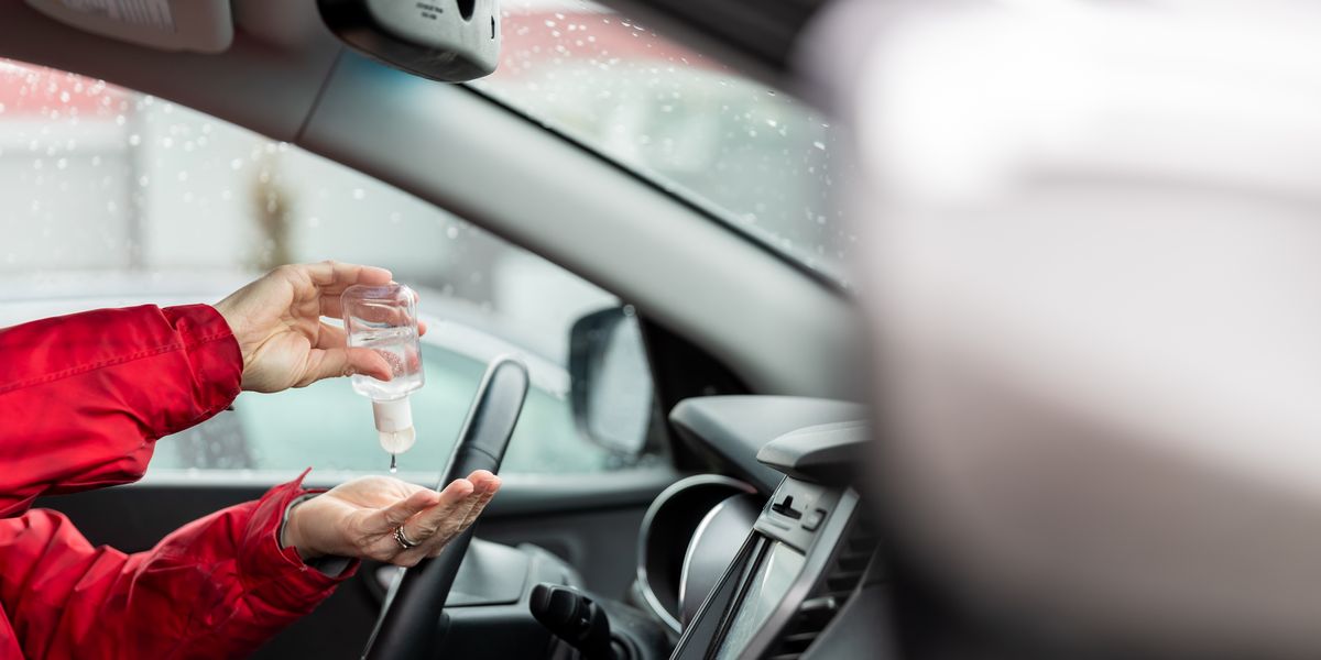 woman using hand sanitizer while sitting in car