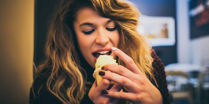 Woman eating cupcake | How to Stop Sugar Cravings