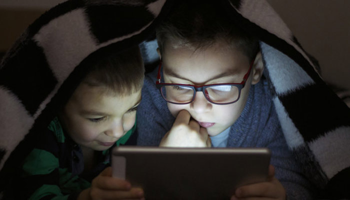 Two kids using tablet under blanket at night | Effect of blue light on sleep