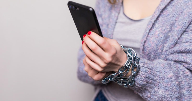 Woman with smartphone chained on her arm | Social Media Addiction