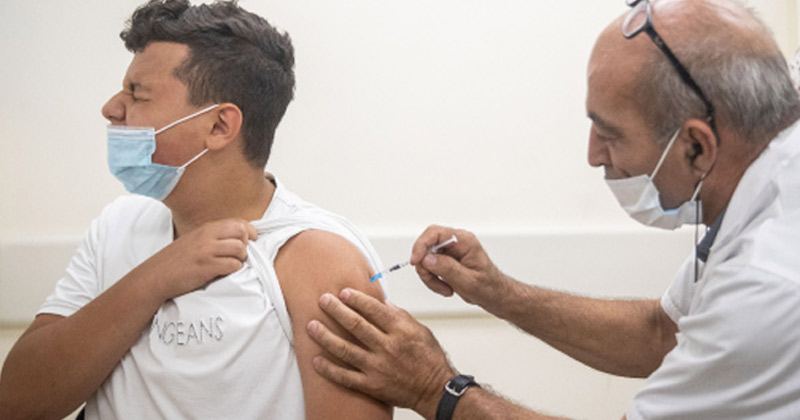Health Worker Administering Vaccine to a person | Israel Rise in Delta Variant Cases